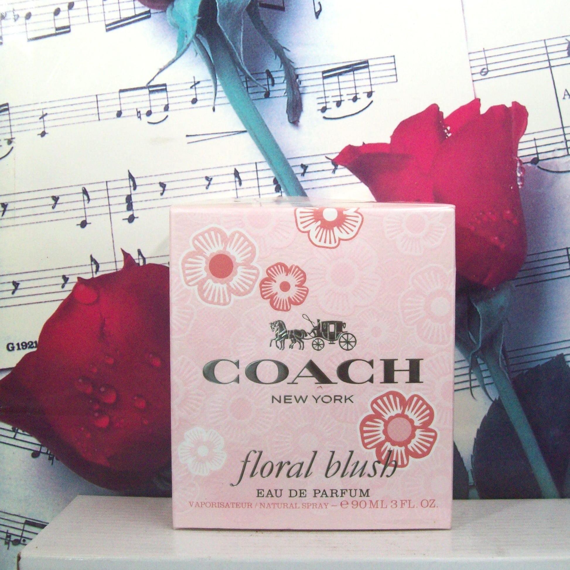 Coach floral blush Eau de Parfum box with red roses and music sheet background