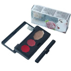 Makeup palette with red and beige colors, compact mirror, and brush next to a branded box on a white background.