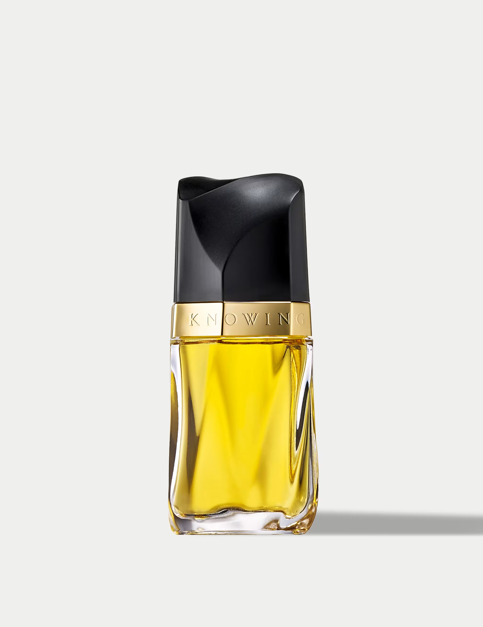 ESTEE LAUDER KNOWING Perfume bottle with black cap and gold label on a light gray background
