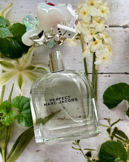 Marc Jacobs Perfect perfume bottle with flowers and leaves on a wooden surface