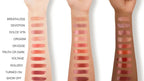 Three hands with various shades of lipstick swatches on a white background